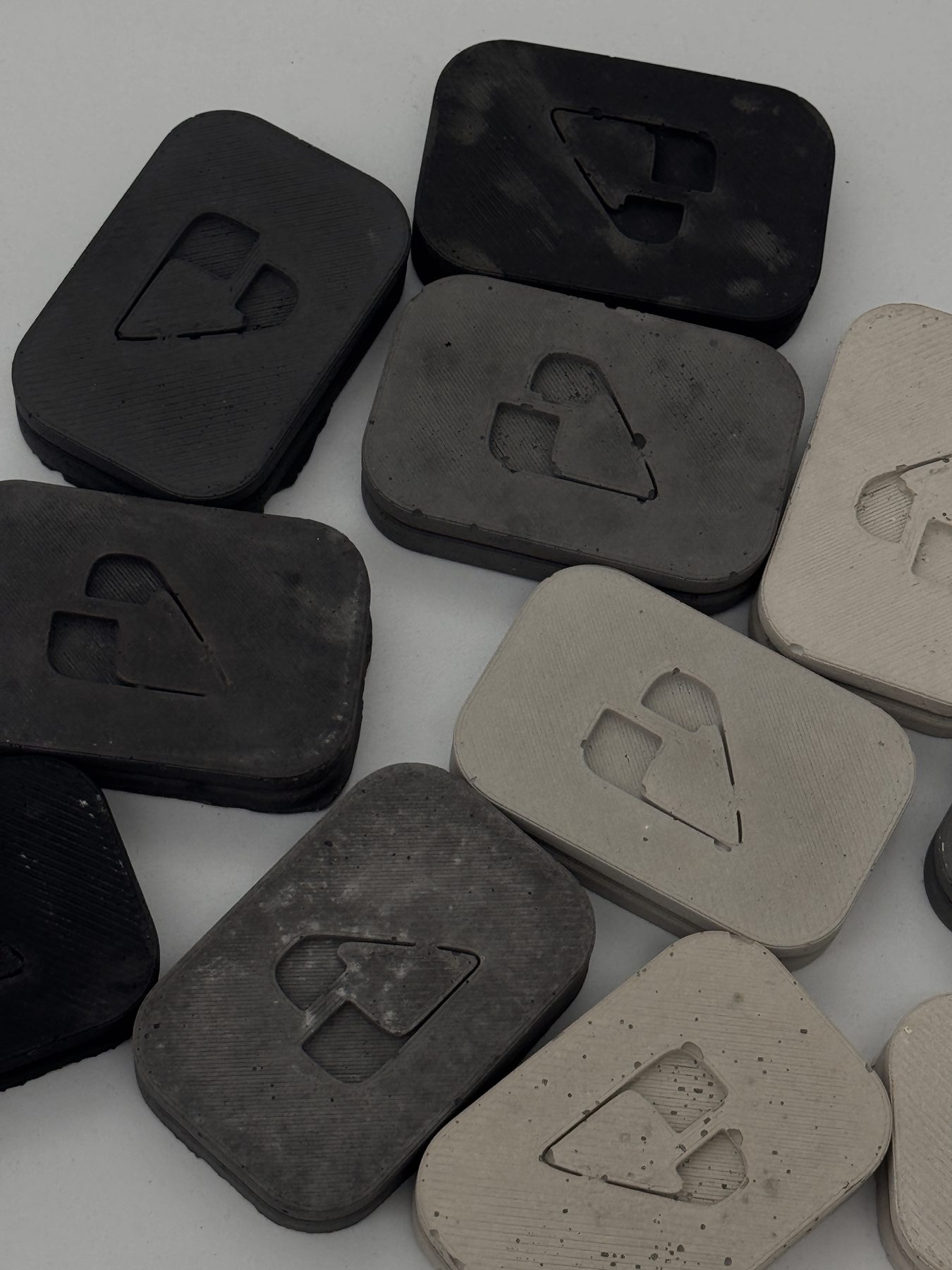 Piezas de concreto negro y gris con la forma del isograma de PAR marcada en la superficie