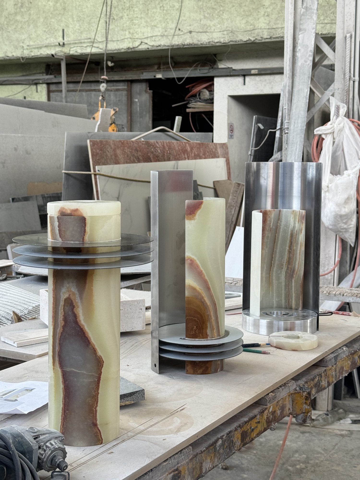 Cilindros de ónix y piezas de metal sobre una mesa en el taller