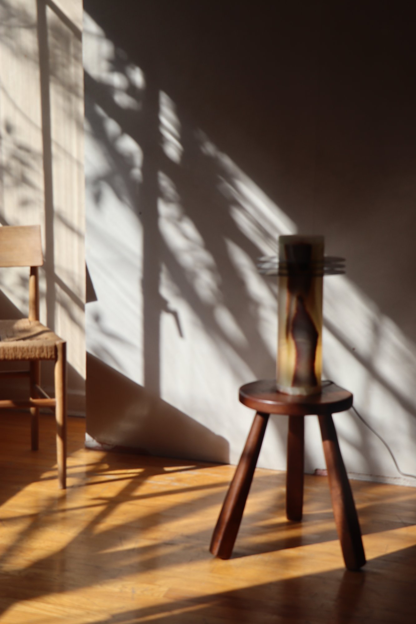 Pieza de ónix sobre un banco de madera oscura, bajo luz cálida y con sombras de hojas en la pared