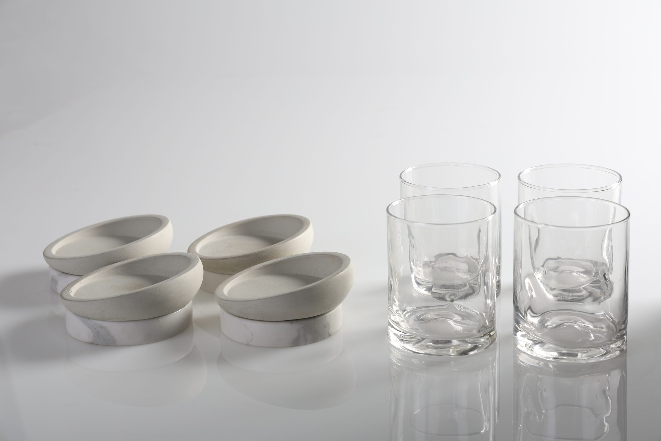 DOPPIO: cuatro platos de concreto y mármol junto a cuatro vasos de vidrio